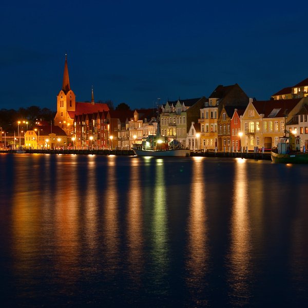 Der Hafen mit einer Kirche und einer bunten Häuserreihe bei Nacht in Sonderburg.